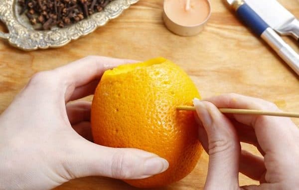 In die Orange werden kleine Löcher gestanzt