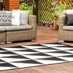 Schwarz-weißer geometrischer Teppichboden auf Holzveranda mit Rattanmöbeln